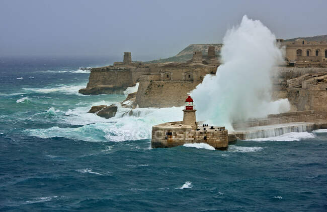 Olas que se estrellan contra el faro de Ricasoli, La Valeta, Malta - foto de stock