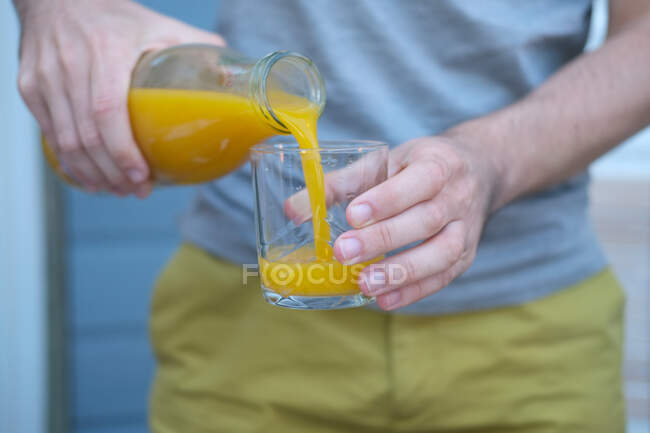 Homem derramando um copo de suco de laranja — Fotografia de Stock