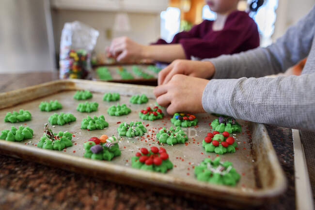 Двое детей стоят на кухне и украшают печенье — стоковое фото