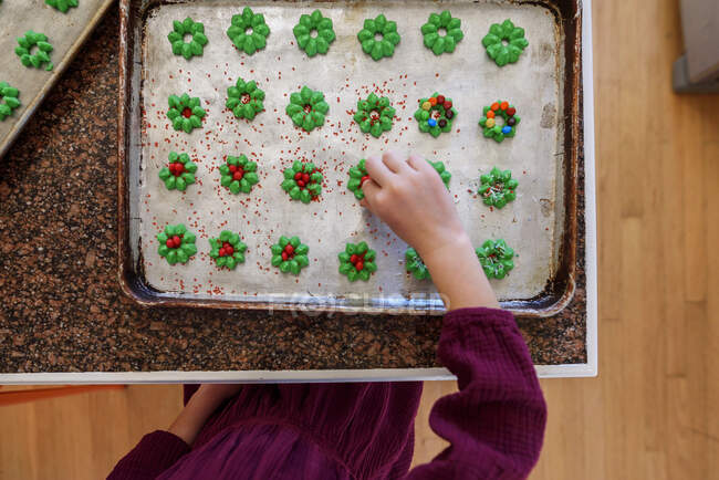 Mädchen steht in der Küche und dekoriert Kekse — Stockfoto