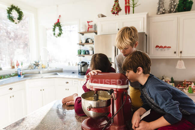 Three children in the kitchen making a cake — Stock Photo