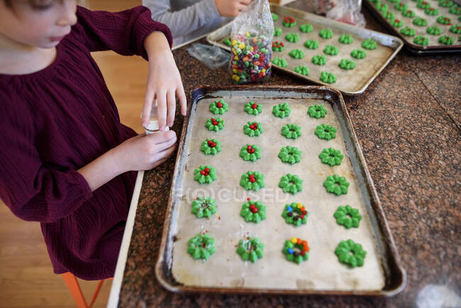 Two children standing in the kitchen decorating cookies — Stock Photo