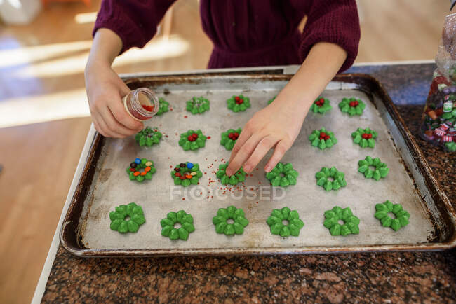 Дівчинка стоїть на кухні і прикрашає печиво. — стокове фото