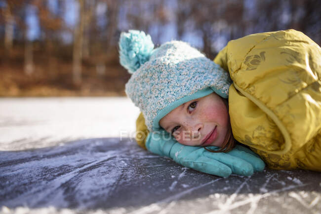 Ritratto di una ragazza sorridente sdraiata su uno stagno ghiacciato, Stati Uniti — Foto stock