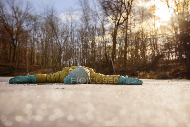 Mädchen liegt mit ausgestreckten Armen auf einem gefrorenen Teich, Vereinigte Staaten — Stockfoto
