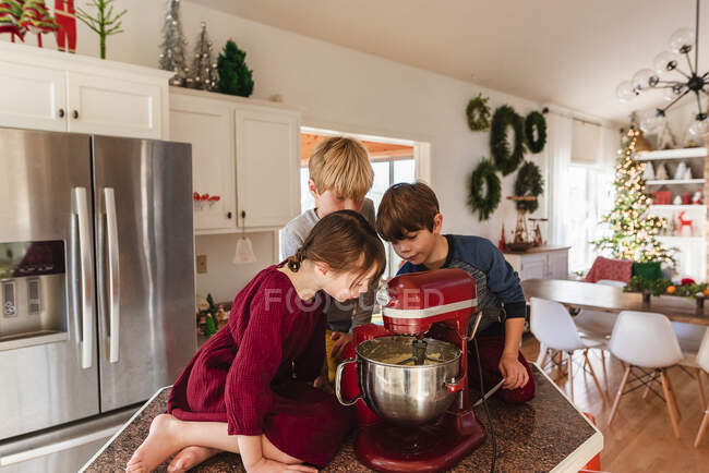 Tres niños en la cocina haciendo un pastel - foto de stock