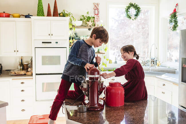 Two children at counter making cake in christmas decorated kitchen interior — Stock Photo
