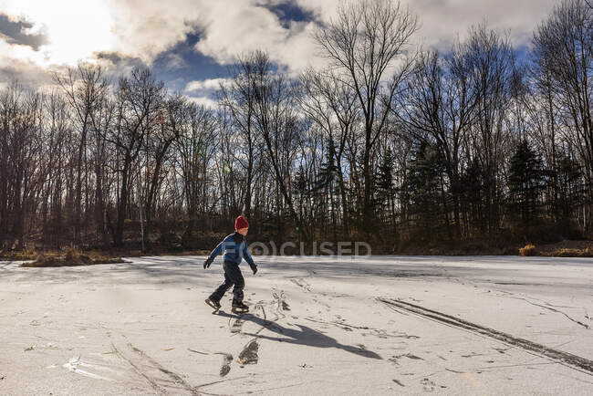 Rapaz patinando no gelo em uma lagoa congelada, Estados Unidos — Fotografia de Stock