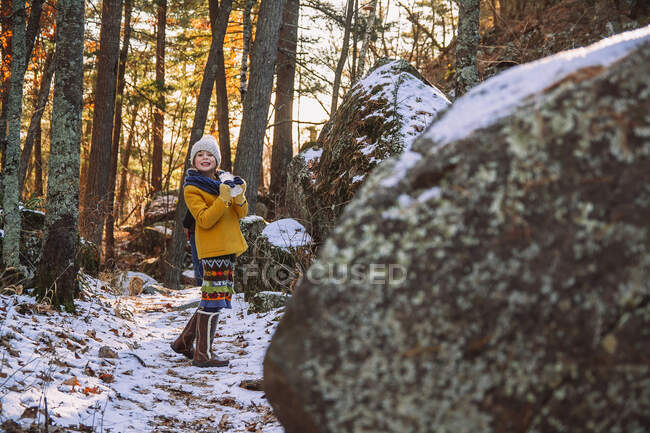 Chica sonriente de pie en el bosque sosteniendo un pedazo de hielo congelado, Estados Unidos - foto de stock