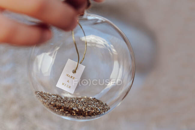 Girl holding a glass bauble with a make a wish message — Stock Photo