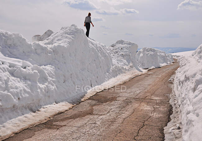 Woman walking on snow pile by a road, Serbia — Stock Photo