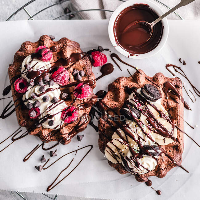 Chocolate waffles with cream, chocolate sauce, fruit and chocolate sandwich cookies — Stock Photo