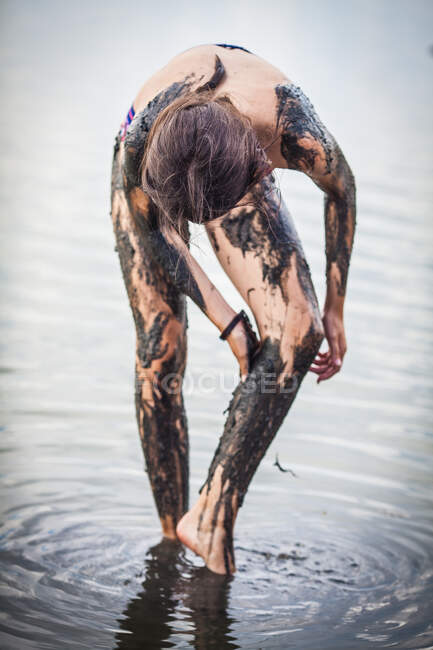 Chica de pie en el lago Atanasovsko cubriéndose de barro, Burgas, Bulgaria - foto de stock