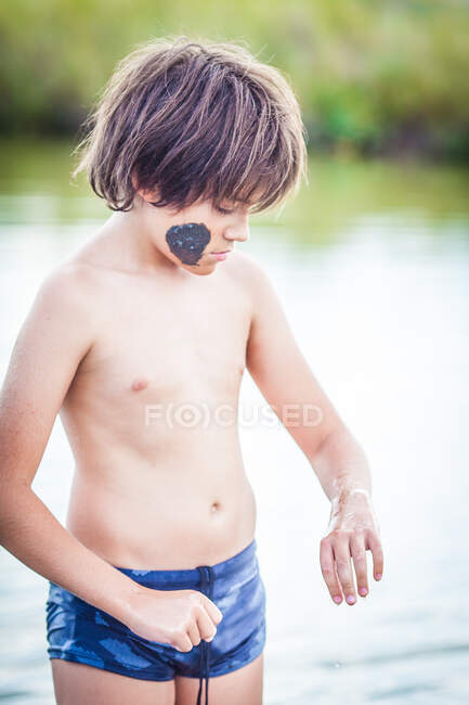 Niño de pie en el lago Atanasovsko con barro en la cara, Burgas, Bulgaria - foto de stock