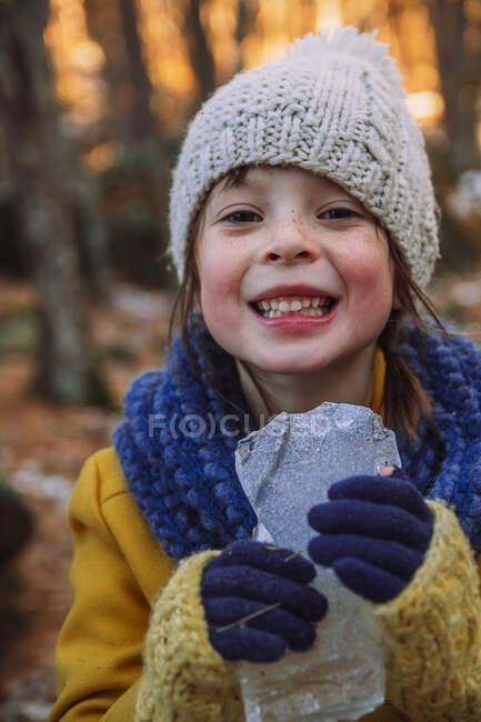 Smiling girl standing in the forest holding a piece of ice, United States — Stock Photo