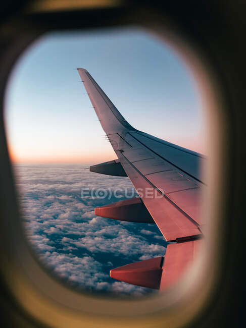 Aile d'avion à travers une fenêtre d'avion — Photo de stock