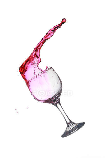 Copa cayendo con derramamiento de vino tinto aislado sobre fondo blanco - foto de stock