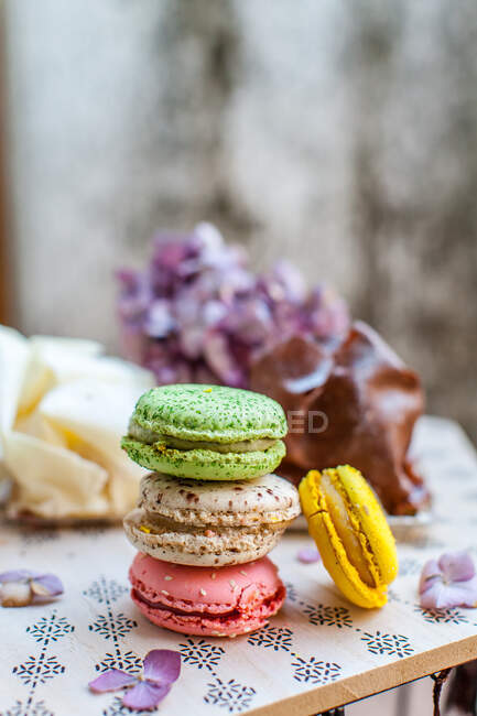 Macarons sucrés colorés avec dessert et fleurs sur la table, vue rapprochée — Photo de stock