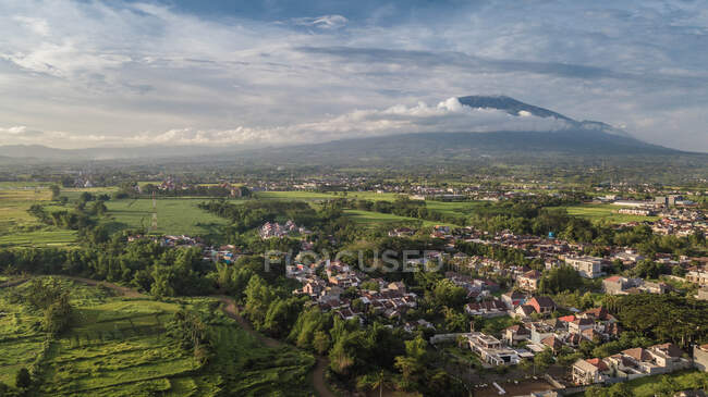 Pintoresca vista de la pequeña ciudad en el valle verde cerca de las montañas - foto de stock