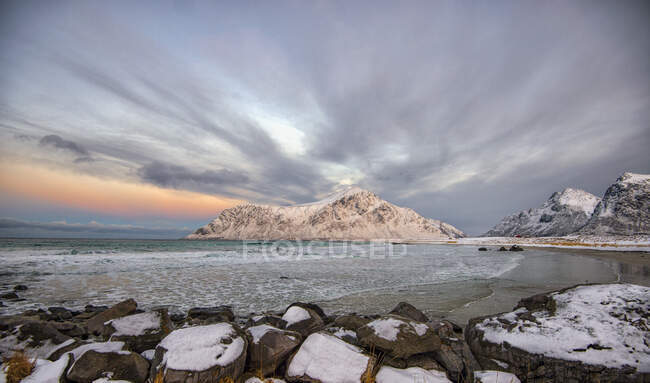 Picturesque view of snowy coast and wavy sea at sunset — Stock Photo