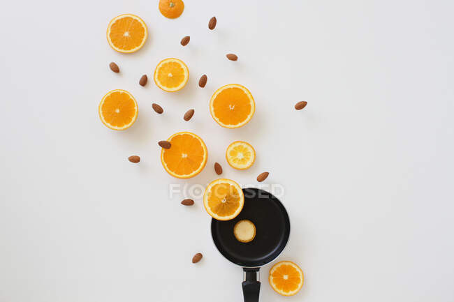 Small pan with oranges and almonds on white background — Stock Photo
