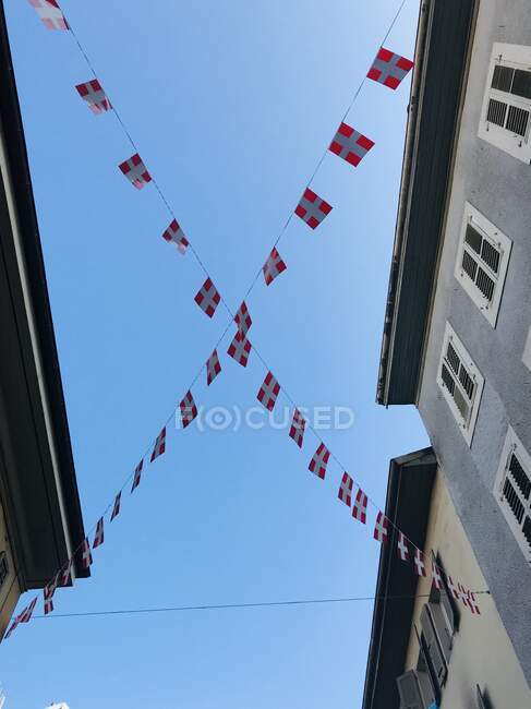 Vista de baixo ângulo das bandeiras suíças penduradas na rua — Fotografia de Stock