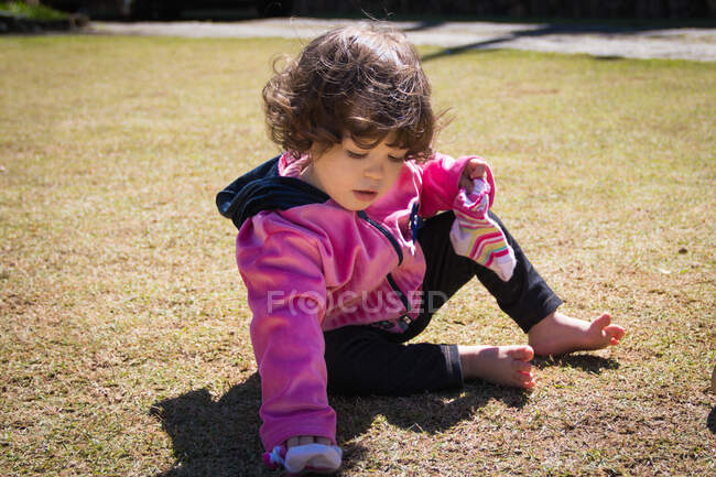 Chica sentada en un parque sosteniendo sus calcetines - foto de stock