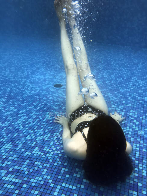 Mulher deitada debaixo d 'água no fundo de uma piscina — Fotografia de Stock