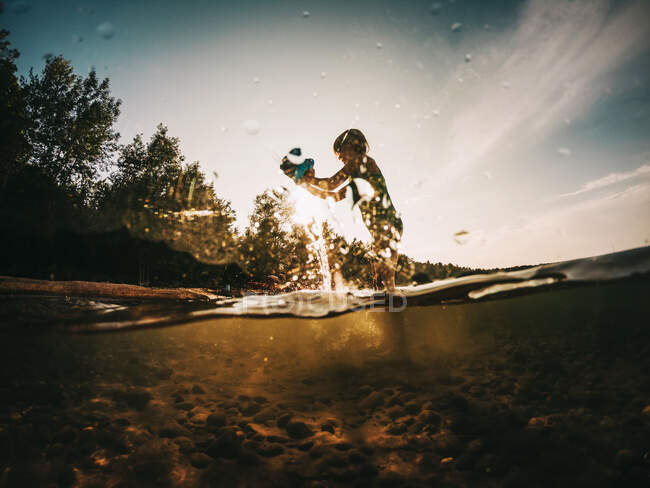 Mädchen steht in einem See und leert einen Eimer Wasser, Lake Superior, Vereinigte Staaten — Stockfoto