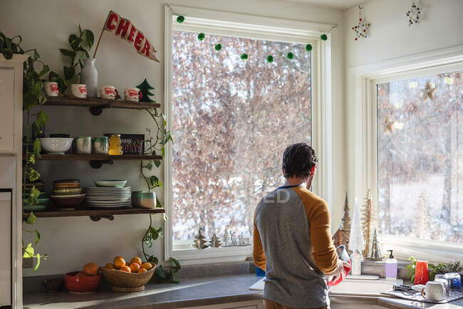 Мужчина, стоящий на кухне и моющий посуду — стоковое фото