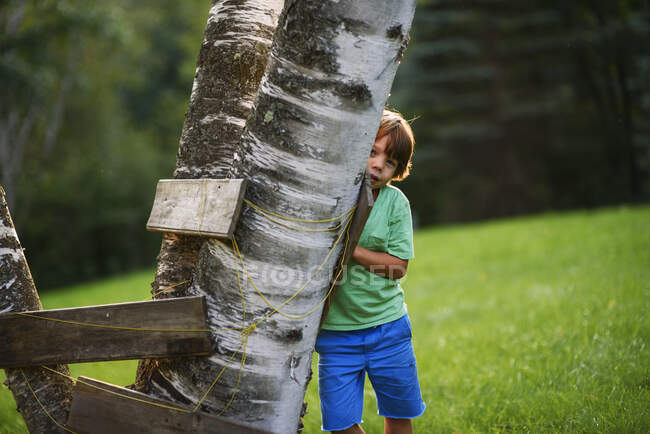 Ragazzo nascosto dietro un forte di alberi, Stati Uniti — Foto stock
