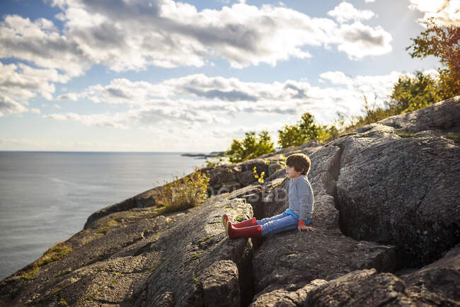 Junge sitzt auf Felsen an einem See, Lake Superior Provincial Park, Vereinigte Staaten — Stockfoto