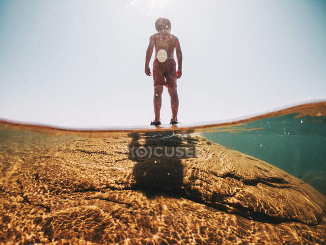 Junge steht auf einem Felsen im Lake Superior, USA — Stockfoto