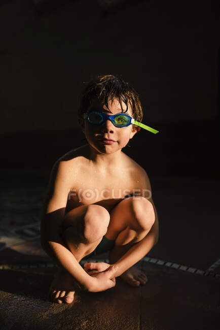 Retrato de menino vestindo óculos subaquáticos sentados à luz do sol — Fotografia de Stock