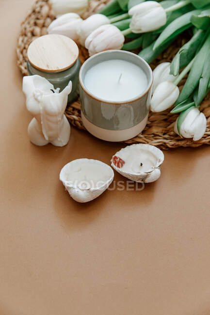 Weiße Kaffeetasse mit Blumen und Kerzen auf hellem Hintergrund. — Stockfoto