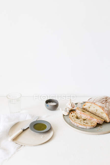 Чабатта хлеб, оливковое масло, соль и стакан воды — стоковое фото