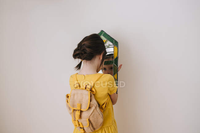 Rear view of a Girl looking at her reflection in a mirror — Stock Photo