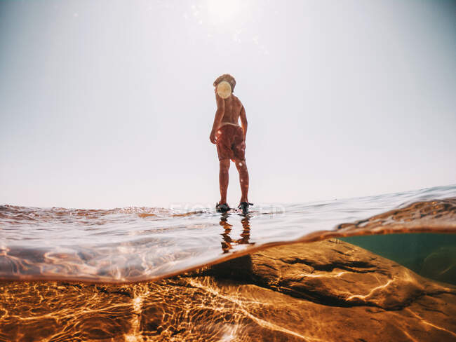 Junge steht auf einem Felsen im Lake Superior, USA — Stockfoto
