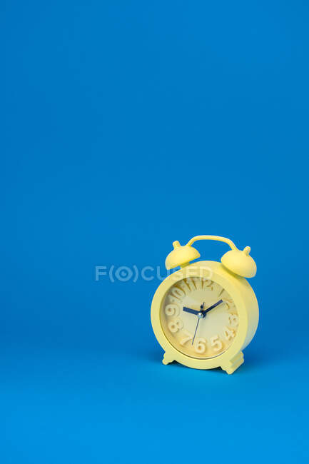 Жовтий годинник проти синього фону — стокове фото