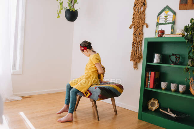 Ragazza seduta su uno sgabello mettere sul suo zaino — Foto stock