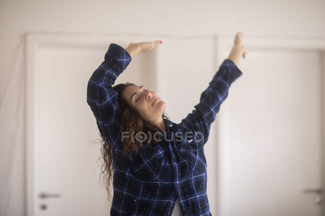 Woman standing in the living room stretching — Stock Photo