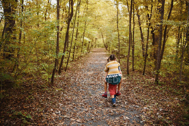 Boy giving his sister a piggy back in the woods, United States — Stock Photo