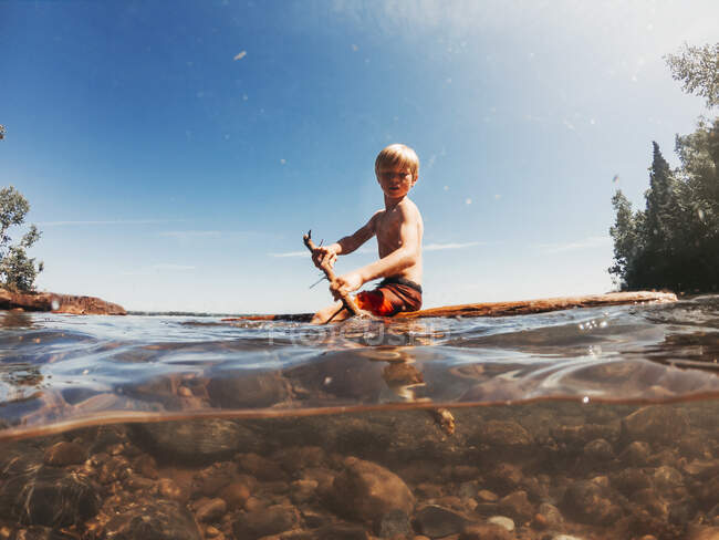 Мальчик, плывущий по озеру на деревянном плоту, озеро Верхнее, США — стоковое фото