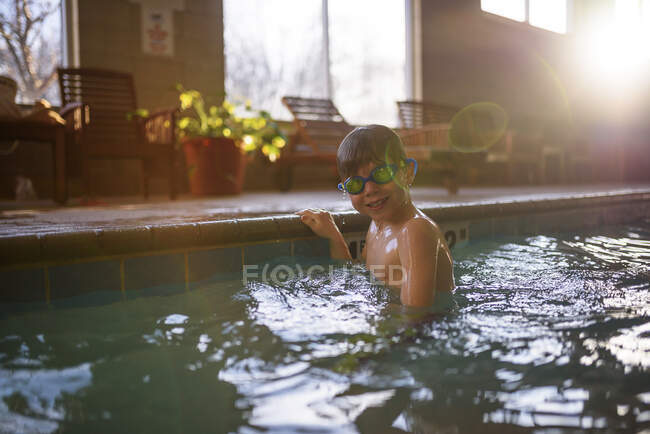 Boy in pool wearing underwater goggles, looking at camera — Stock Photo