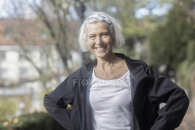 Улыбающаяся пожилая женщина, стоящая в парке — стоковое фото