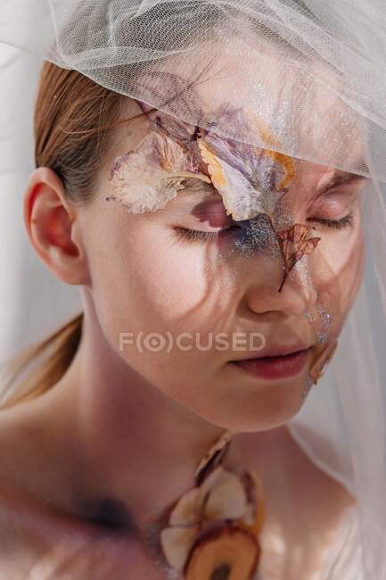 Konzeptuelles Schönheitsporträt einer Frau, die einen Schleier mit getrockneten Blumen im Gesicht und am Hals trägt — Stockfoto
