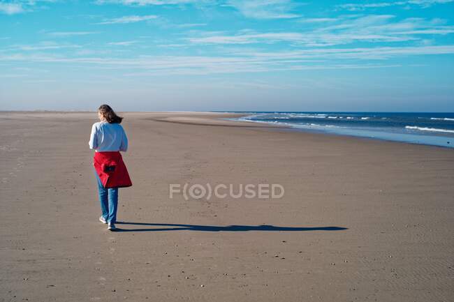Женщина, идущая вдоль пляжа осенью, Юист, Восточная Фризия, Нижняя Саксония, Германия — стоковое фото