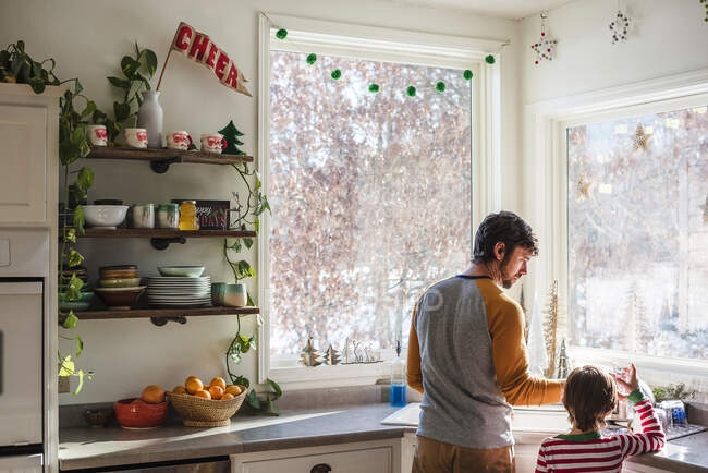 Отец и сын стоят на кухне и моют посуду. — стоковое фото