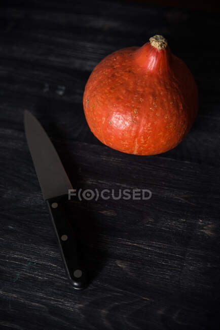 Abóbora laranja e faca na mesa de madeira, vista de perto — Fotografia de Stock