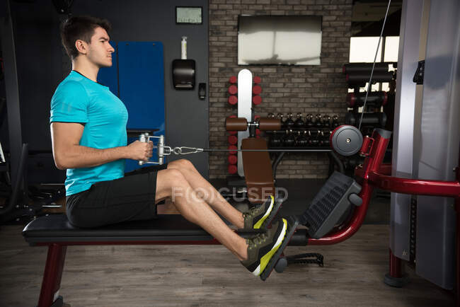 Homem usando uma máquina de remo em um ginásio — Fotografia de Stock
